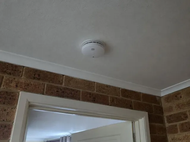 Ceiling smoke alarm above a hallway in a brick home in Tarro
